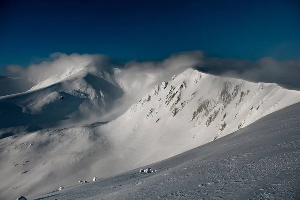 Vista panorâmica sobre picos de montanha nevados cobertos de nuvens em dia ensolarado — Fotografia de Stock