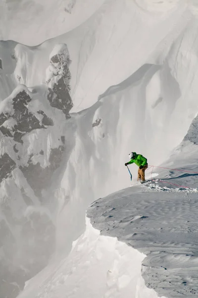 Man skiër met klimuitrusting bevestigd zichzelf met een veiligheidstouw en houdt een schep — Stockfoto