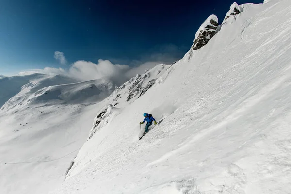 Manliga friåkare skidor i sidled ner på snöig bergssluttning — Stockfoto