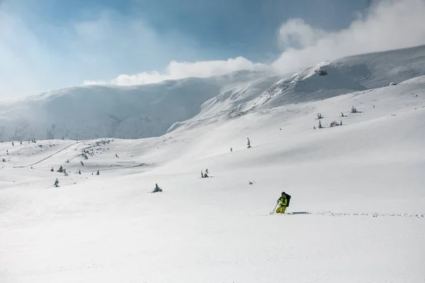 Uśmiechnięty narciarz w jasnym stroju narciarskim, kasku i googlach stojących w śniegu po kolana — Zdjęcie stockowe