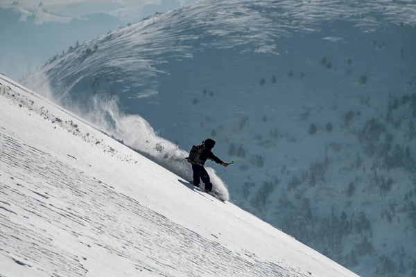 头戴专业相机的滑雪板手头盔快速滑落积雪覆盖的斜坡 — 图库照片