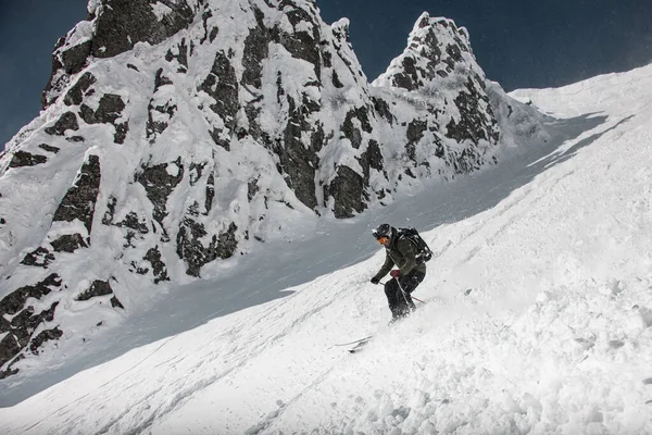 Esquiador vestido con ropa deportiva marrón y negro con cámara go-pro oh su casco deslizándose por las laderas cubiertas de nieve — Foto de Stock