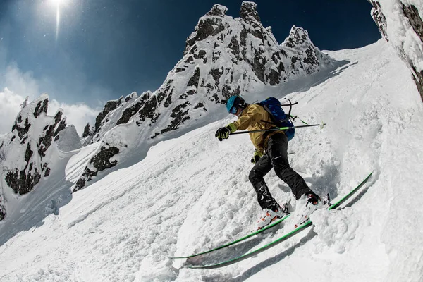 Skier dressed in beige and black sportswear with go-pro camera oh his helmet sliding down snow-covered slopes — Fotografia de Stock