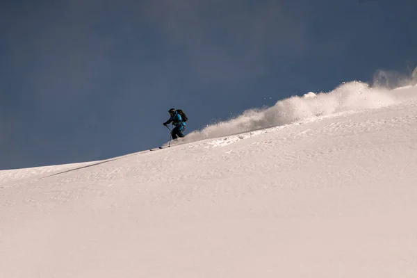 Great view on active snowboarder riding down from snowy mountain on splitboard and splashes snow. — Stock Photo, Image