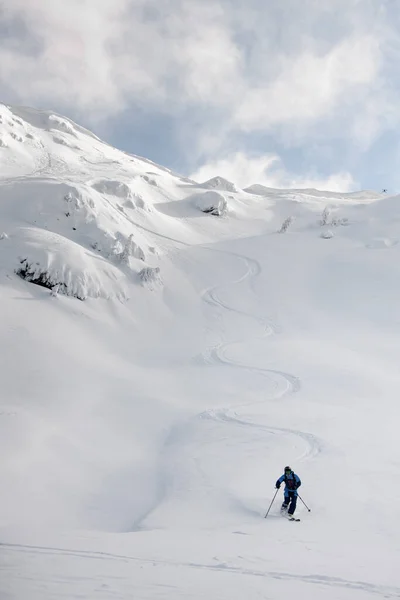 Snowboarder atlético passeio para baixo a neve em pó intocada. Paisagem montanhosa coberta de neve pitoresca rodeia — Fotografia de Stock