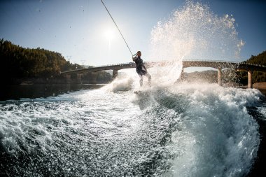 Su sıçratan nehir dalgası ve kaldırma tahtasının üzerinde ip tutan adamın güzel manzarası.