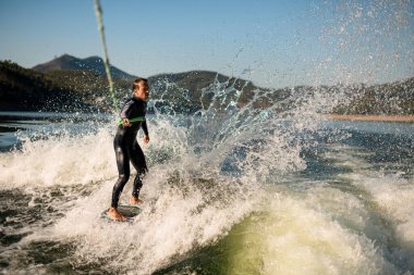 Adam ipin sapını tutuyor ve güçlü bir şekilde su sıçratma tahtasına biniyor..