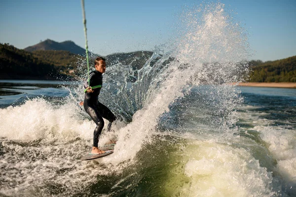 Aktif insan binicisi ipin sapını tutar ve güçlü bir şekilde su sıçratma tahtasının üzerinde süzülür..