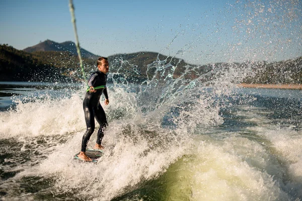Adam ipin sapını tutuyor ve güçlü bir şekilde su sıçratma tahtasına biniyor..