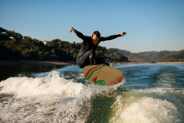 Atletik wakesurfer melompat pada papan wakesurf di atas gelombang sungai — Stok Foto