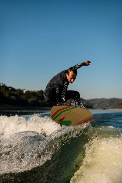 Athletic wakesurfer skillfully jumping on a wakesurf board over the river waves — 스톡 사진