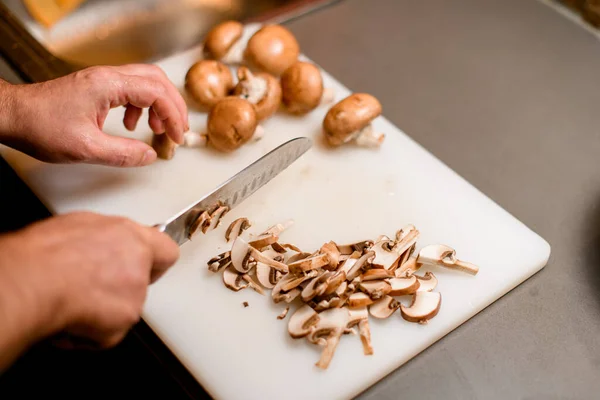Selective focus on sliced champignons and male hand chopping mushrooms with a knife — Zdjęcie stockowe