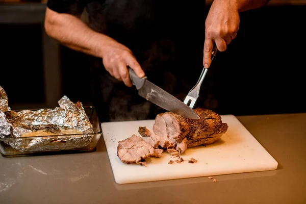 Man chef cuts cooked fried meat on white cutting board. — Stockfoto