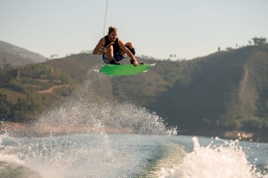 Wakeboard 'lu bir adamın su sıçratarak havada zıplaması harika bir manzara.