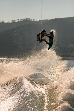 Su sıçratan dalganın güzel manzarası ve aktif bir adamın Wakeboard 'la havaya zıplaması.