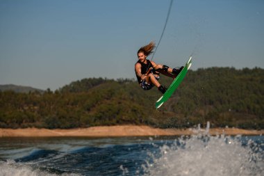 Yakışıklı, sağlıklı, aktif bir adam ustaca atlıyor Wakeboard 'da dalgalanan dalgaların üzerinden
