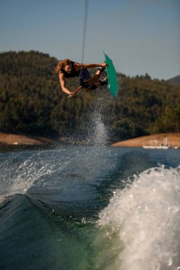 Wakeboard 'lu bir adam ustalıkla atlıyor dalgaların üzerinden.