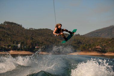 Wakeboard 'lu bir adam ustaca atlıyor dalgaların üzerinden.