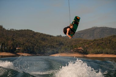 Dalgaların üzerinden ustalıkla atlayan Wakeboard 'lu adamın görüntüsü.