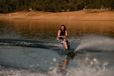 Aktif adam ipi tutuyor ve usta bir şekilde nehirde wakeboard sürüyor..