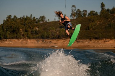 İnsanoğlunun Wakeboard 'da uçan dalgaların üzerinden ustalıkla atlarken çekilmiş fotoğrafı.
