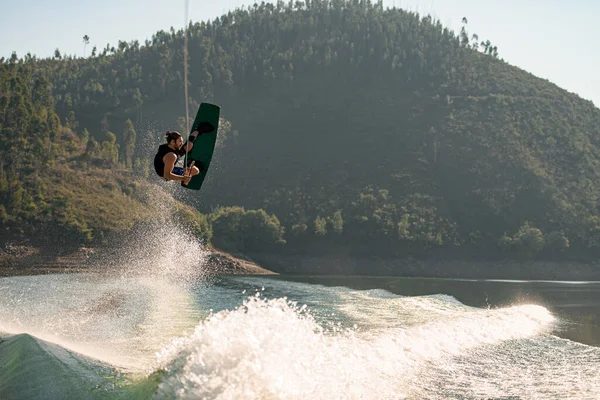 Active strong man making trick in jump time with wakeboard — ストック写真