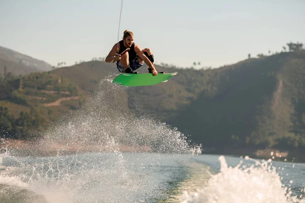Wonderful view of man with wakeboard jumping in the air over splashing water — Photo