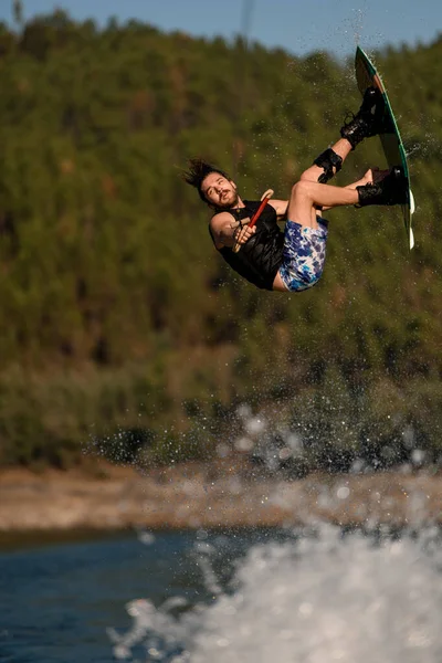 Primer plano de la energía masculina wakeboarder saltar y voltear en wakeboard —  Fotos de Stock