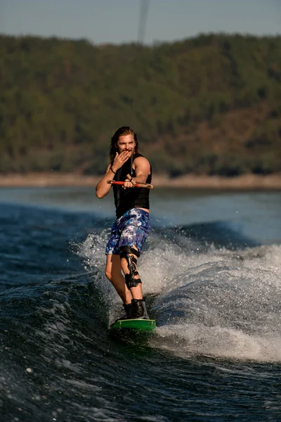 Atletik sakallı adam halatı tutuyor ve nehir dalgası boyunca aktif olarak dengede duruyor.