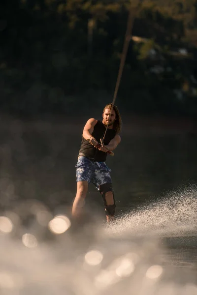 View on man holding rope and riding on the river wave on wakeboard — ストック写真