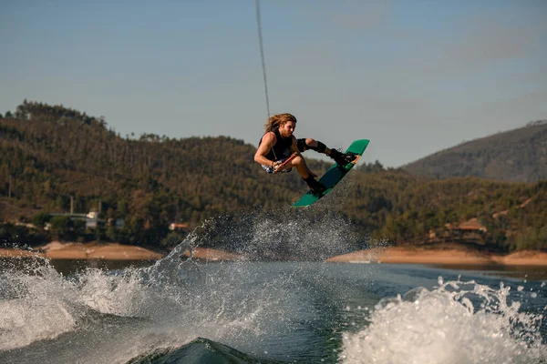 Man with wakeboard masterfully jumping high over splashing wave. — Zdjęcie stockowe