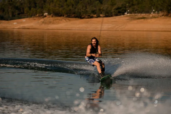 Aktif adam ipi tutuyor ve usta bir şekilde nehirde wakeboard sürüyor..