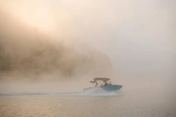 Csodálatos kilátás a hajón gyorsan lebeg a víz hátterében sziluett hegy köd — Stock Fotó