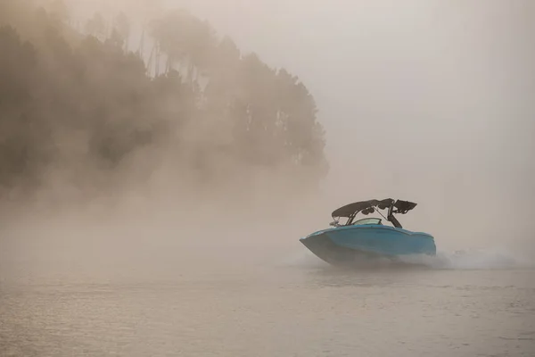 Festői kilátás a hajón gyorsan lebeg a vízen hátterében sziluett domb köd — Stock Fotó