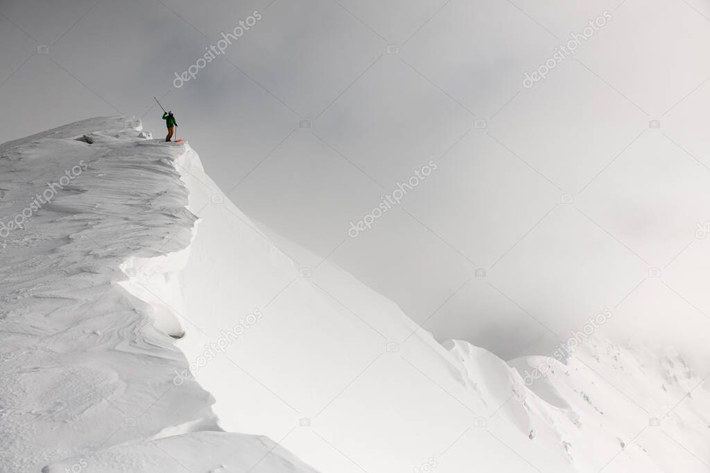 gorgeous view on skier in bright jacket with skitour equipment on splitboard on mountain at sunny winter day