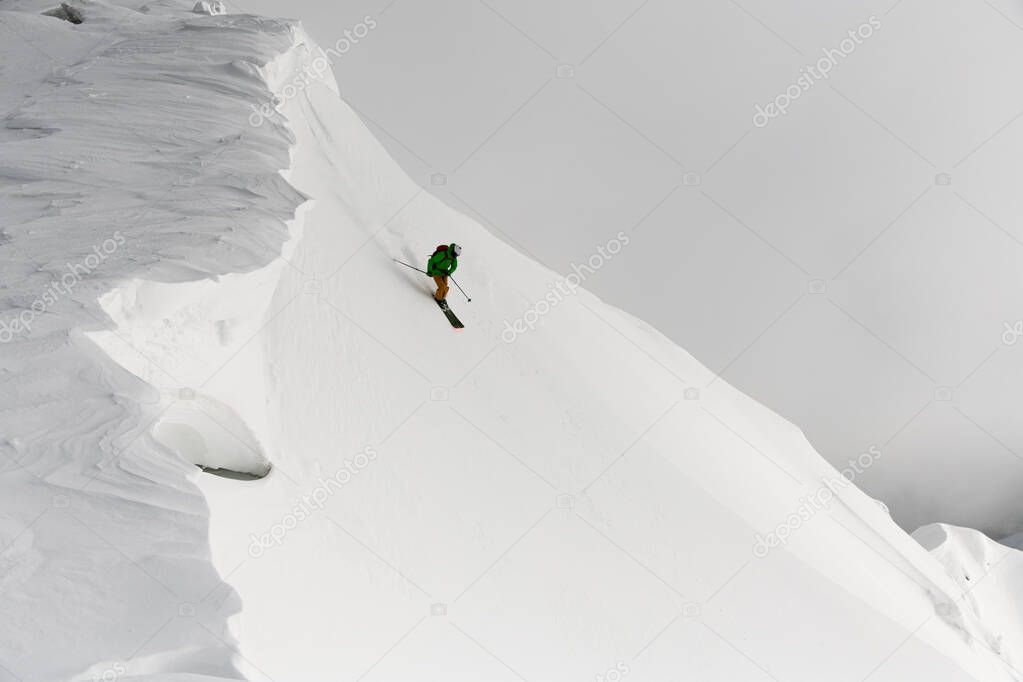 Man splitboard freerider masterfully rides down from top of ridge. Ski touring in mountains, winter freeride extreme sport