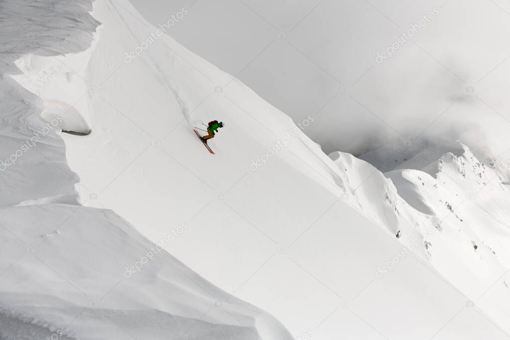 View from drone on man freerider riding down from top of ridge. Ski touring in mountains, extreme sport