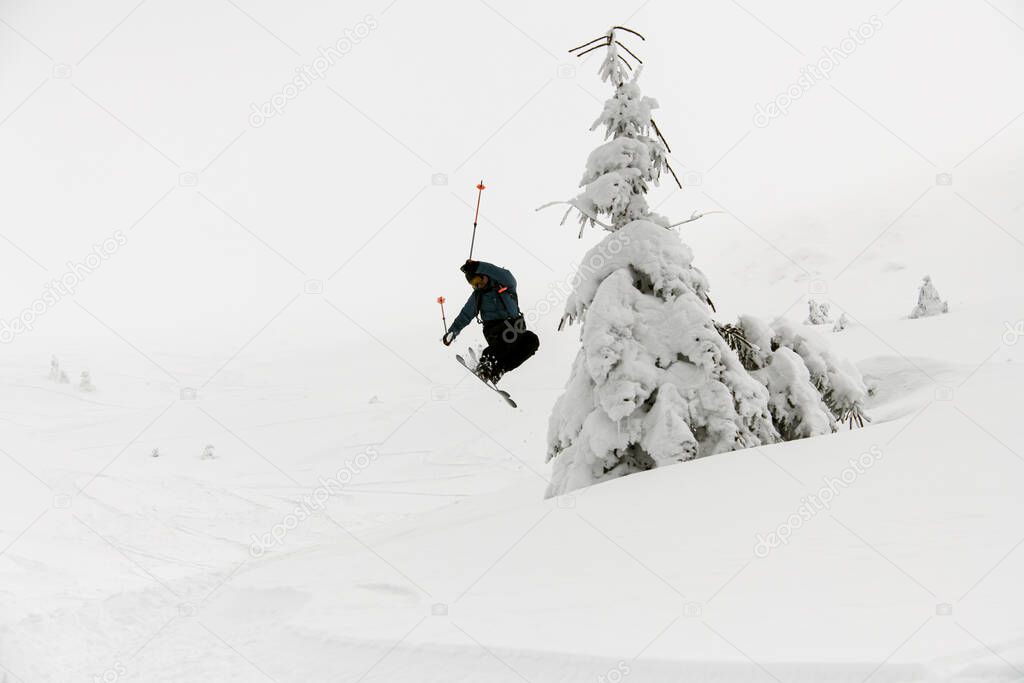athlete skier masterfully jumping over slopes of snow-capped mountains. Ski touring in mountains, winter freeride extreme sport.