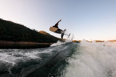 Aktif adam sıçrama zamanında gökyüzü arka planında folyo wakeboard ile numara yapıyor. Yaz zamanı su sporları aktivitesi