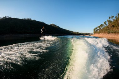 Su sıçratan dalganın muhteşem manzarası ve folyonun üzerinde siyah dalgıç kıyafetli bir adam.
