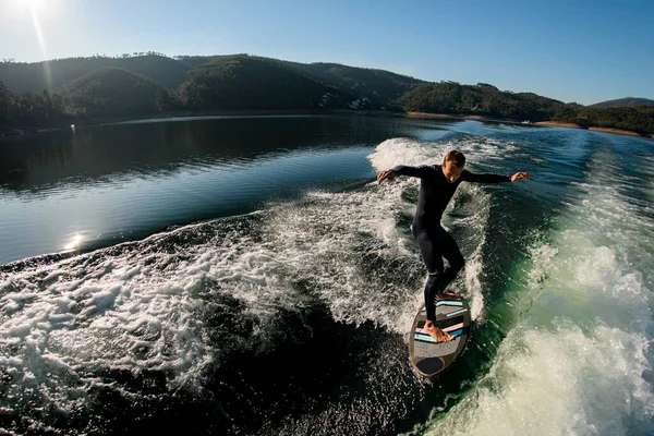 잠수복을 사람의 웨이크 보드에 튀기는 파도에 에너지적으로 균형을 사람을 Wakesurfer — 스톡 사진