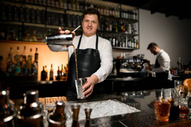 Profesyonel erkek barmen kokteylleri bir bardaktan diğerine ustaca doldurur. Kokteyl hazırlama süreci