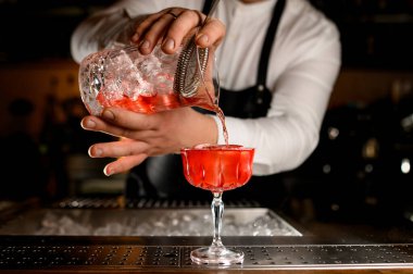 Güzel şeffaf bir kadehin büyüleyici manzarası. Parlak bir içeceğin kristal karıştırıcı bardaktan döküldüğü.