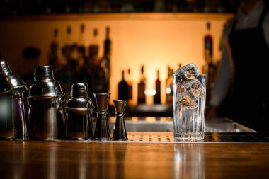 Buz küplü şeffaf bir cam manzarası ve bulanık bir arka plandaki bir tezgahın üzerinde birkaç çelik titretici.