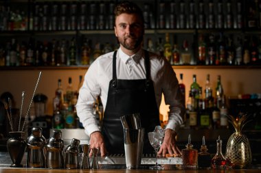 Bar tezgahında güzel bir manzara, arka planda çelik aletler ve erkek barmen.