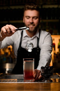 Bardakta alkollü kokteyl olan buzlu bardakta harika bir yakın plan. Arkadaki barmen.