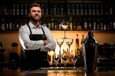 Boş şampanya bardakları ve tezgahın üzerindeki büyük sallamadan yapılmış kulenin muhteşem manzarası. Arka planda erkek barmen