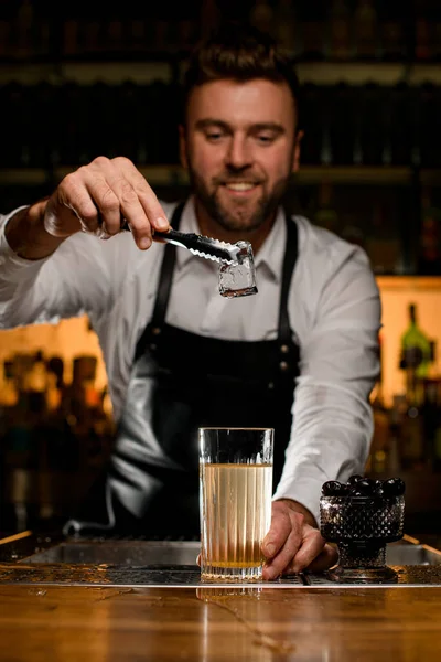 Męski Barman Trzyma Ręku Szczypce Kostką Lodu Nad Szklanką Koktajlem — Zdjęcie stockowe