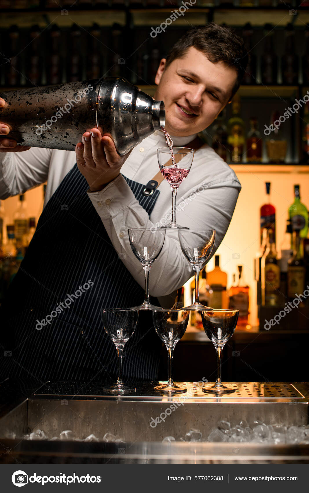 Bartender Holds In Hand Steel Jigger And Pours Drink From Bottle