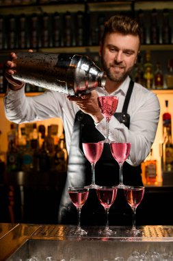 Barmenin büyük bir bardaktan lezzetli bir kokteyl döktüğü bardaktan yapılmış kulenin güzel manzarası.